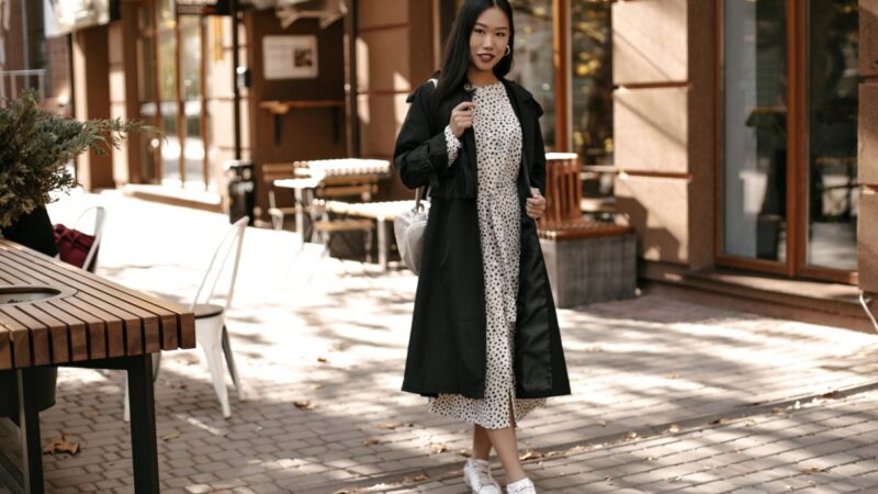 fulllength portrait brunette asian woman midi white dress black trench coat stands outside near street cafe 1.jpg